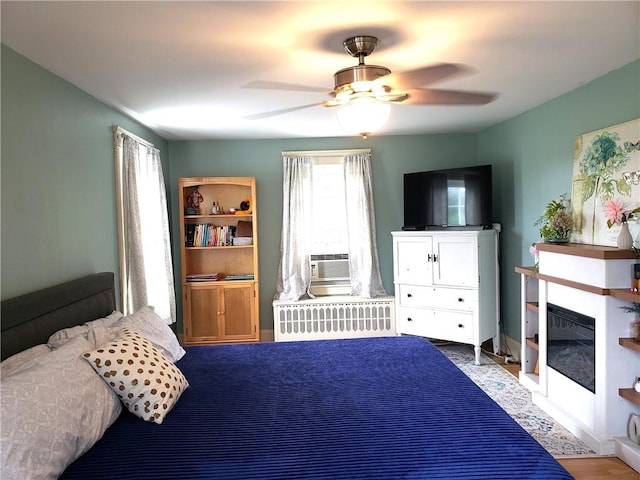 603 Wakefield St, West Warwick, RI 02893 - bedroom featuring cooling unit, radiator heating unit, a glass covered fireplace, and a ceiling fan