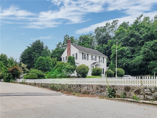 603 Wakefield St, West Warwick, RI 02893 - view of front of property featuring a chimney, a fenced front yard, and view of wooded area