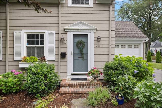 221 Trinity St, Warwick, RI 02886 - view of exterior entry featuring a shingled roof and an attached garage