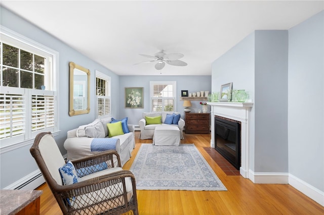 221 Trinity St, Warwick, RI 02886 - living area featuring light wood-style flooring, a ceiling fan, a baseboard radiator, and a fireplace with flush hearth