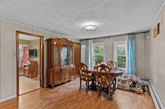 10 Foundry St, Central Falls, RI 02863 - dining area with a baseboard radiator, ornamental molding, light wood-type flooring, a textured ceiling, and wooden walls