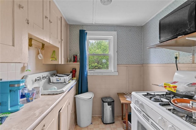 10 Foundry St, Central Falls, RI 02863 - kitchen featuring white gas stove, light countertops, tile walls, wainscoting, and wallpapered walls