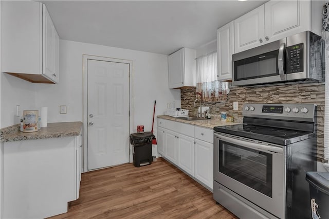 1 Ware St, Providence, RI 02907 - kitchen with appliances with stainless steel finishes, backsplash, white cabinets, and light wood-style flooring