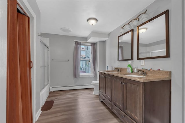 1 Ware St, Providence, RI 02907 - bathroom with a baseboard radiator, double vanity, wood finished floors, and bath / shower combo with glass door