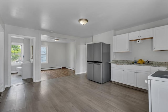 1 Ware St, Providence, RI 02907 - kitchen with freestanding refrigerator, baseboard heating, range, white cabinets, and wood finished floors
