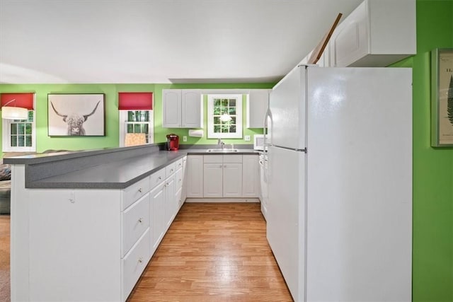 825 Matteson Rd, Coventry, RI 02816 - kitchen with white appliances, a peninsula, dark countertops, light wood finished floors, and white cabinets