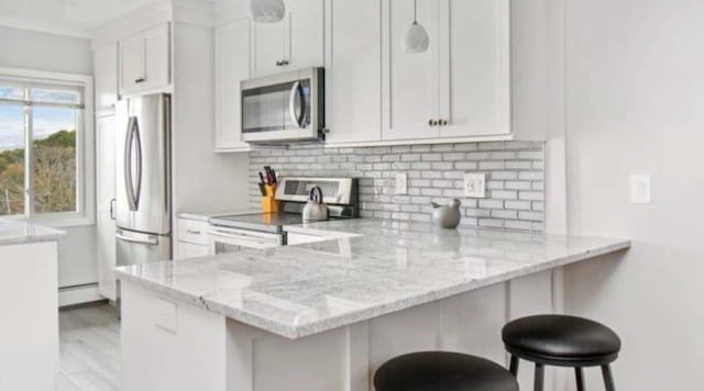 400 Narragansett Pkwy Unit Sb9, Warwick, RI 02888 - kitchen featuring stainless steel appliances, tasteful backsplash, light stone countertops, and a breakfast bar