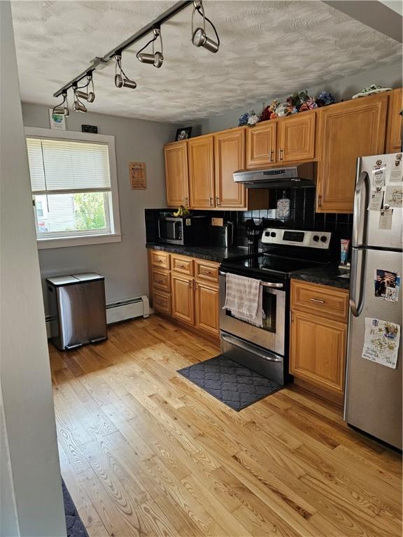 250 Arnold Rd, Coventry, RI 02816 - kitchen featuring appliances with stainless steel finishes, under cabinet range hood, dark countertops, a baseboard heating unit, and tasteful backsplash
