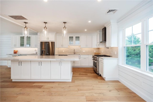 5 Williams St Unit 4, Warwick, RI 02818 - kitchen with high end appliances, wall chimney range hood, white cabinetry, decorative backsplash, and glass insert cabinets