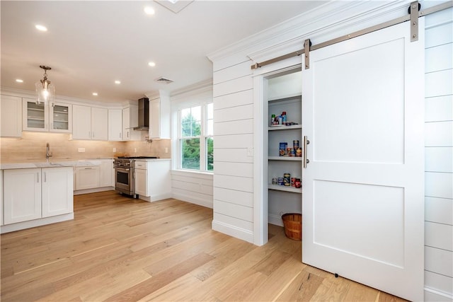 5 Williams St Unit 4, Warwick, RI 02818 - kitchen with high end stainless steel range, wall chimney range hood, a barn door, light wood finished floors, and recessed lighting