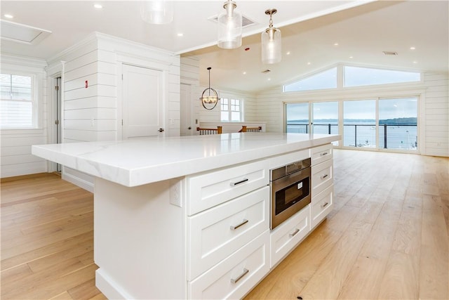 5 Williams St Unit 4, Warwick, RI 02818 - kitchen with white cabinetry, stainless steel microwave, vaulted ceiling, light wood-style floors, and hanging light fixtures