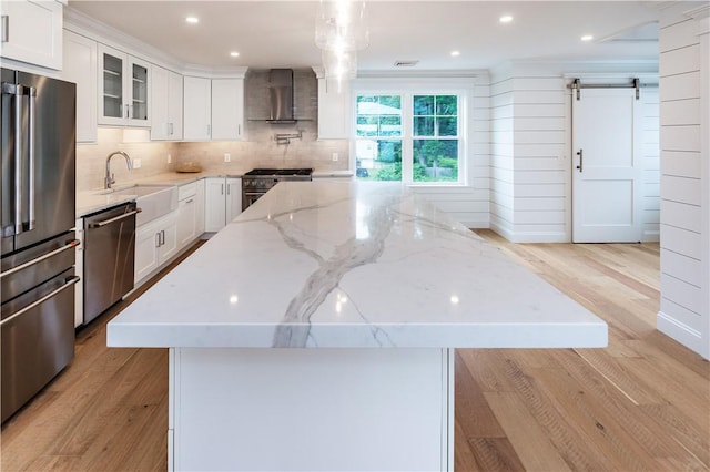 5 Williams St Unit 4, Warwick, RI 02818 - kitchen featuring wall chimney exhaust hood, appliances with stainless steel finishes, a center island, a barn door, and light wood-type flooring