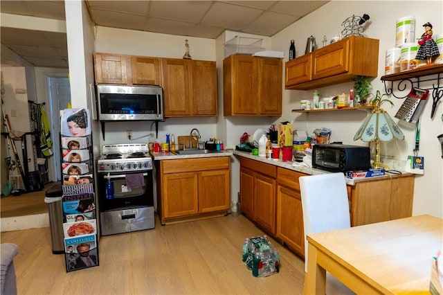 61 Cyr St, Providence, RI 02905 - kitchen featuring stainless steel appliances, a drop ceiling, light wood-style flooring, light countertops, and brown cabinetry