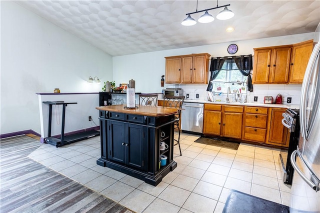 61 Cyr St, Providence, RI 02905 - kitchen with appliances with stainless steel finishes, brown cabinetry, tasteful backsplash, and a center island