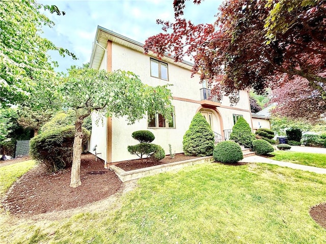 74 Plymouth Rd, East Providence, RI 02914 - view of front of home with a front lawn, stucco siding, and a balcony