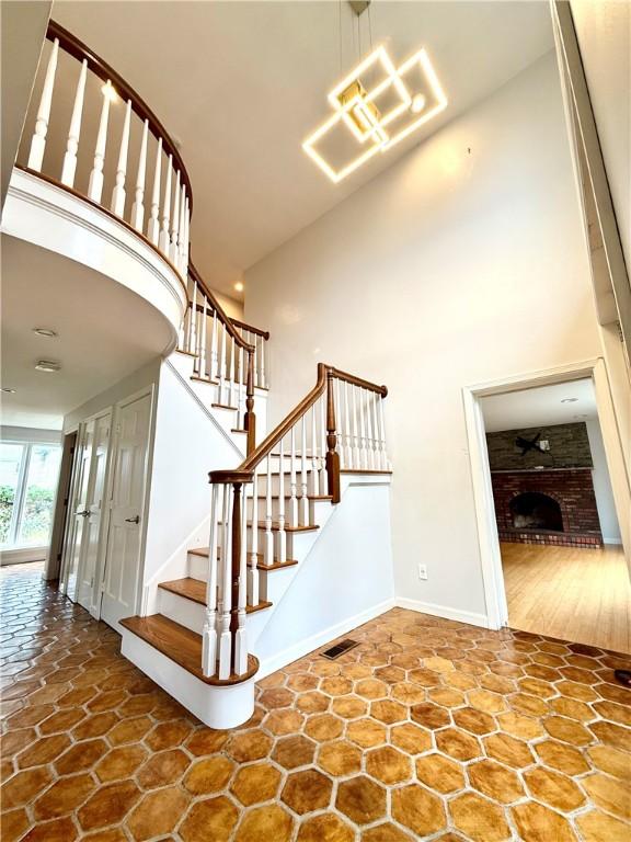 74 Plymouth Rd, East Providence, RI 02914 - staircase with a towering ceiling, a fireplace, and a chandelier