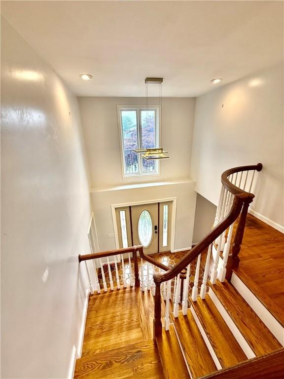 74 Plymouth Rd, East Providence, RI 02914 - stairs featuring wood finished floors and a chandelier