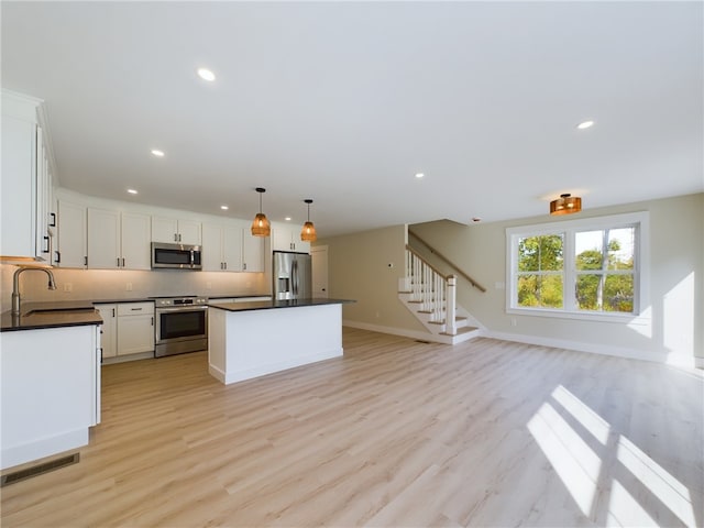 7 Carolina Nooseneck Rd Unit C, Richmond, RI 02898 - kitchen featuring stainless steel appliances, dark countertops, open floor plan, a center island, and white cabinets