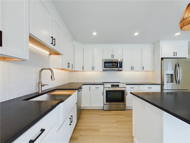 7 Carolina Nooseneck Rd Unit C, Richmond, RI 02898 - kitchen with stainless steel appliances, dark countertops, light wood-style floors, white cabinetry, and backsplash