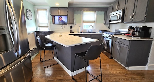 92 Silver Spring Ave, East Providence, RI 02915 - kitchen featuring appliances with stainless steel finishes, a breakfast bar, a peninsula, light countertops, and dark wood-style flooring