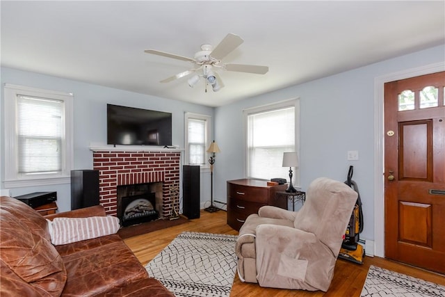 36 Walton St, Providence, RI 02908 - living room featuring wood finished floors, baseboard heating, a ceiling fan, a baseboard heating unit, and a brick fireplace