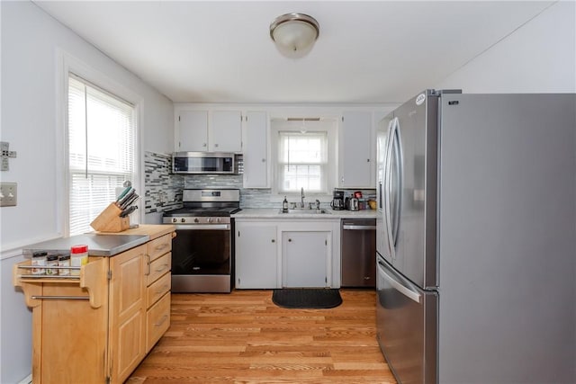 36 Walton St, Providence, RI 02908 - kitchen featuring stainless steel appliances, light wood-style flooring, light countertops, tasteful backsplash, and white cabinetry