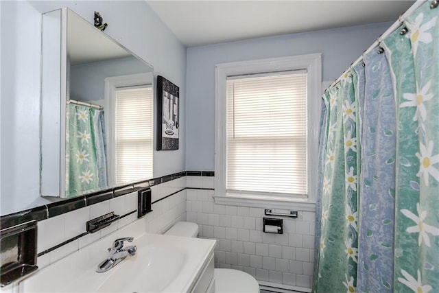 36 Walton St, Providence, RI 02908 - full bath with tile walls, vanity, healthy amount of natural light, a baseboard radiator, and a wainscoted wall