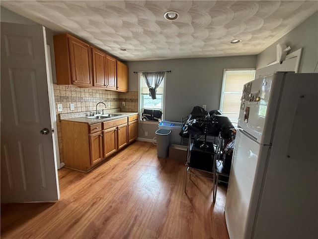 141 Pomona Ave, Providence, RI 02908 - kitchen featuring freestanding refrigerator, brown cabinetry, light countertops, backsplash, and light wood finished floors