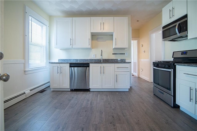 1397 Chalkstone Ave, Providence, RI 02909 - kitchen featuring stainless steel appliances, a baseboard radiator, white cabinets, a wainscoted wall, and dark wood-type flooring