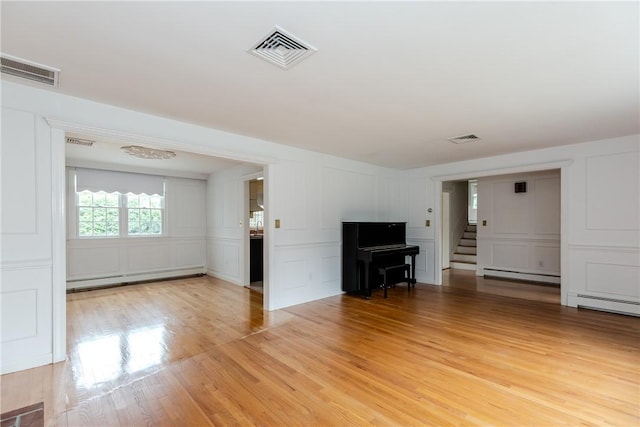 11 Macintosh Dr, Smithfield, RI 02828 - unfurnished living room with a decorative wall, a baseboard heating unit, light wood-style flooring, stairway, and baseboard heating