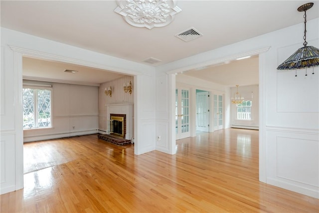 11 Macintosh Dr, Smithfield, RI 02828 - unfurnished living room featuring a chandelier, baseboard heating, a decorative wall, light wood-style flooring, and plenty of natural light