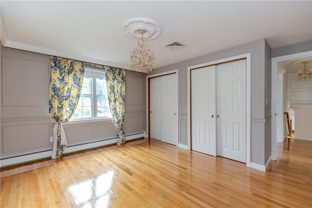 11 Macintosh Dr, Smithfield, RI 02828 - unfurnished bedroom featuring a chandelier, a decorative wall, baseboard heating, two closets, and light wood finished floors