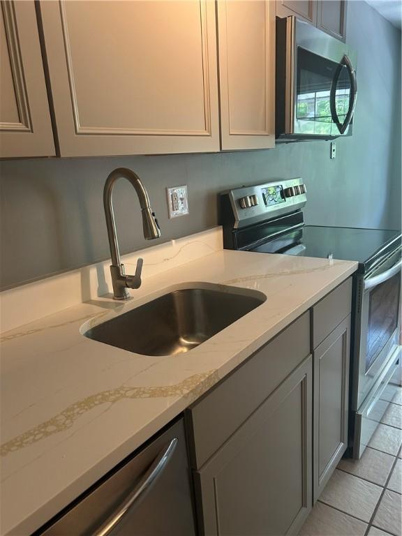 25 Bullocks Point Ave Unit 5C, East Providence, RI 02915 - kitchen with appliances with stainless steel finishes, gray cabinets, light stone counters, and light tile patterned floors