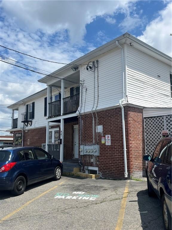 877 Central Ave, Pawtucket, RI 02861 - view of front of house featuring uncovered parking, brick siding, and a balcony