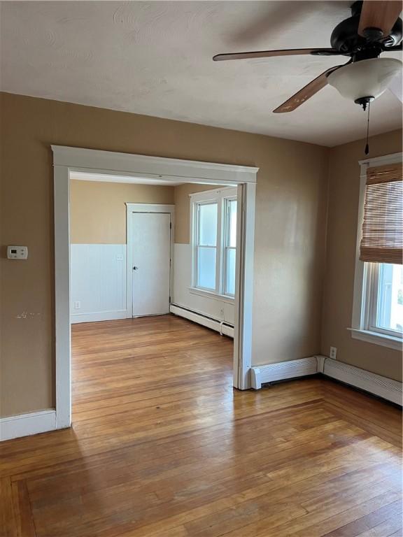 877 Central Ave, Pawtucket, RI 02861 - unfurnished room featuring a baseboard radiator, ceiling fan, and light wood-style floors