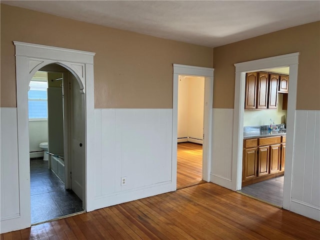877 Central Ave, Pawtucket, RI 02861 - spare room with wainscoting, arched walkways, wood-type flooring, a baseboard radiator, and baseboard heating