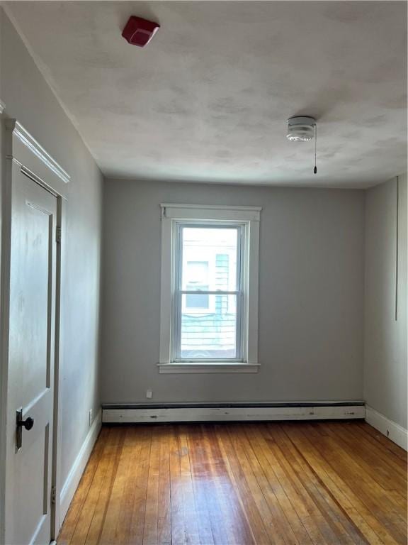 877 Central Ave, Pawtucket, RI 02861 - empty room featuring wood-type flooring and a baseboard heating unit
