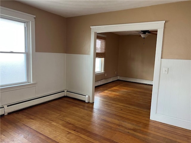 877 Central Ave, Pawtucket, RI 02861 - empty room featuring hardwood / wood-style floors, wainscoting, ceiling fan, a baseboard heating unit, and baseboard heating