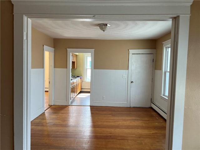 877 Central Ave, Pawtucket, RI 02861 - unfurnished room with wainscoting, wood finished floors, a baseboard heating unit, and baseboard heating