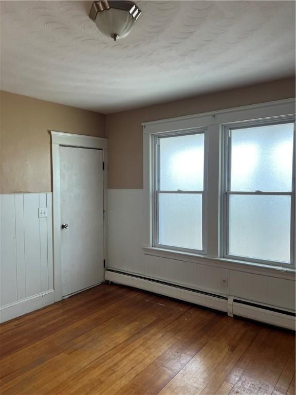 877 Central Ave, Pawtucket, RI 02861 - unfurnished bedroom with baseboard heating, multiple windows, hardwood / wood-style flooring, and a closet