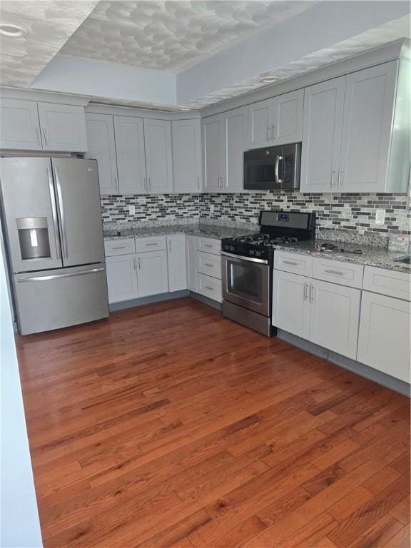 45 Harrison St, Pawtucket, RI 02860 - kitchen with stainless steel appliances, tasteful backsplash, light stone counters, and dark wood-style floors