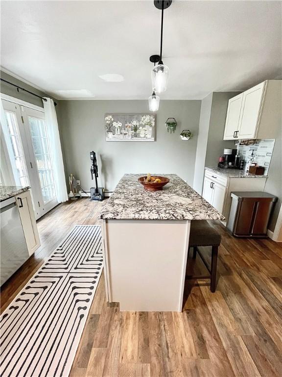 8 Orchard St, West Warwick, RI 02893 - kitchen featuring wood finished floors, light stone counters, white cabinets, and a kitchen island