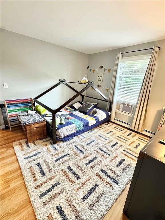 8 Orchard St, West Warwick, RI 02893 - bedroom with light wood-style flooring, a baseboard radiator, and cooling unit