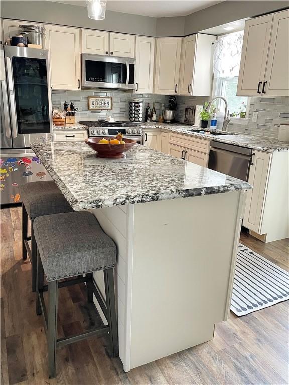 8 Orchard St, West Warwick, RI 02893 - kitchen featuring appliances with stainless steel finishes, decorative backsplash, light stone counters, and a center island