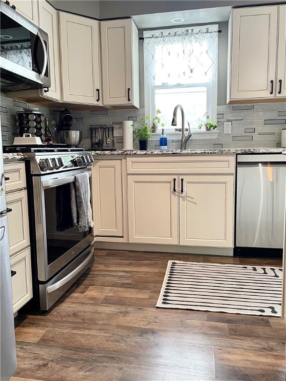 8 Orchard St, West Warwick, RI 02893 - kitchen featuring stainless steel appliances, tasteful backsplash, light stone countertops, dark wood-style floors, and white cabinets