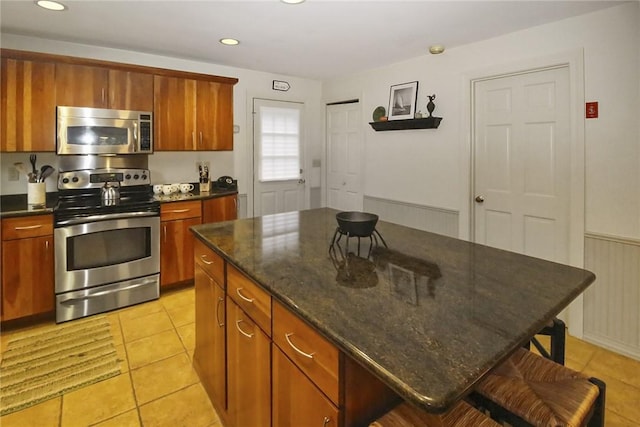 60 Tower Hill Rd, Tiverton, RI 02878 - kitchen with stainless steel appliances, a kitchen island, a kitchen breakfast bar, brown cabinetry, and light tile patterned flooring