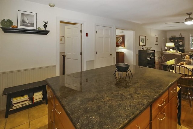 60 Tower Hill Rd, Tiverton, RI 02878 - kitchen with a kitchen island, brown cabinets, open floor plan, a ceiling fan, and dark stone counters