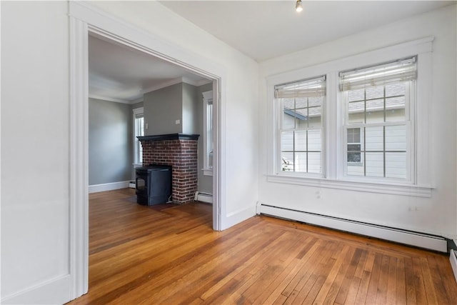 68 Friendly Rd, Cranston, RI 02910 - unfurnished living room with baseboard heating, a wood stove, light wood-type flooring, healthy amount of natural light, and crown molding