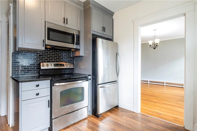 68 Friendly Rd, Cranston, RI 02910 - kitchen with stainless steel appliances, gray cabinetry, decorative backsplash, light wood-style floors, and a chandelier