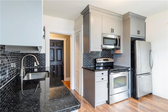 68 Friendly Rd, Cranston, RI 02910 - kitchen with appliances with stainless steel finishes, backsplash, light wood-style flooring, and dark stone counters